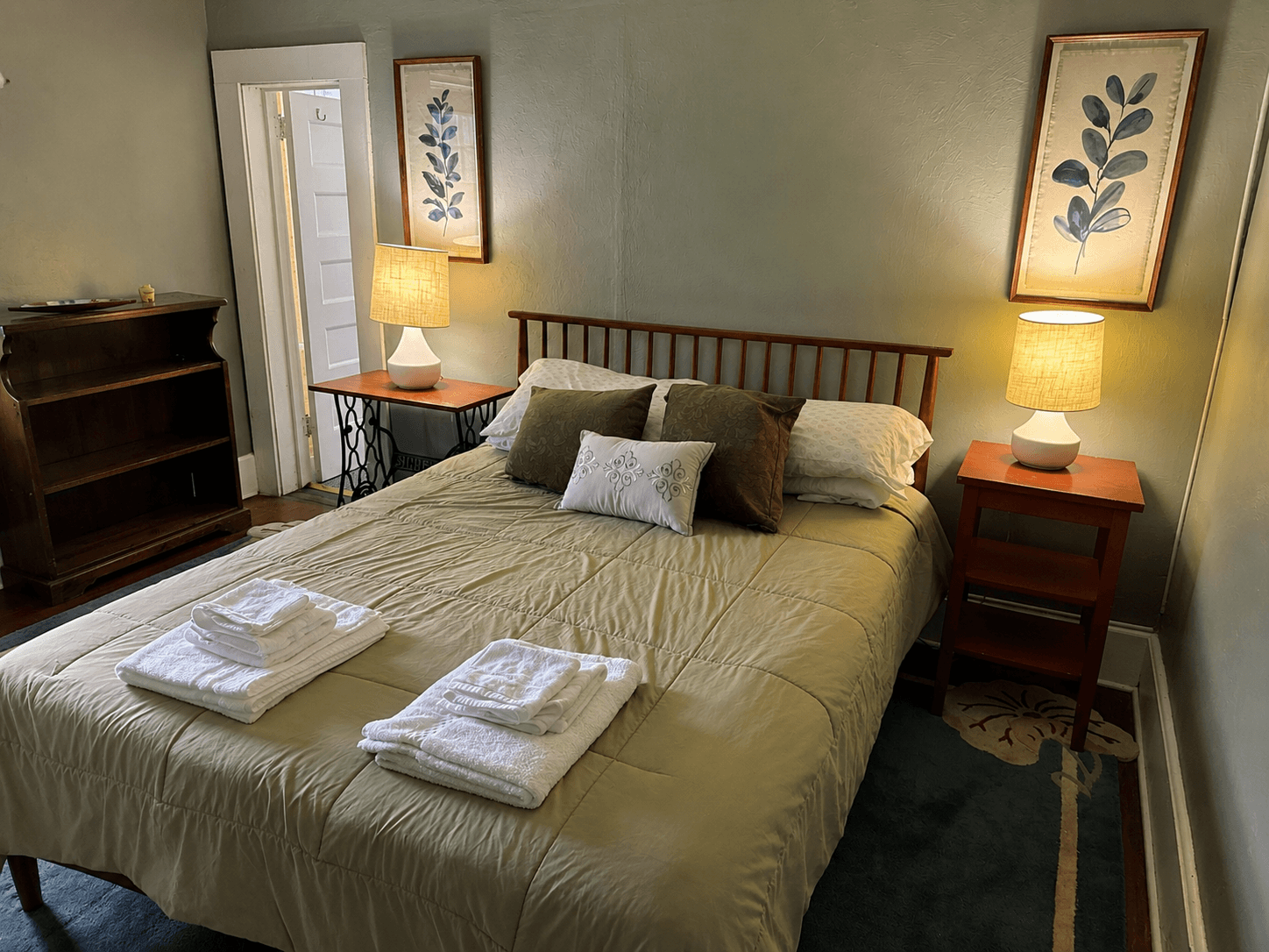 queen bed, side tables, pictures on wall, bookcase, door