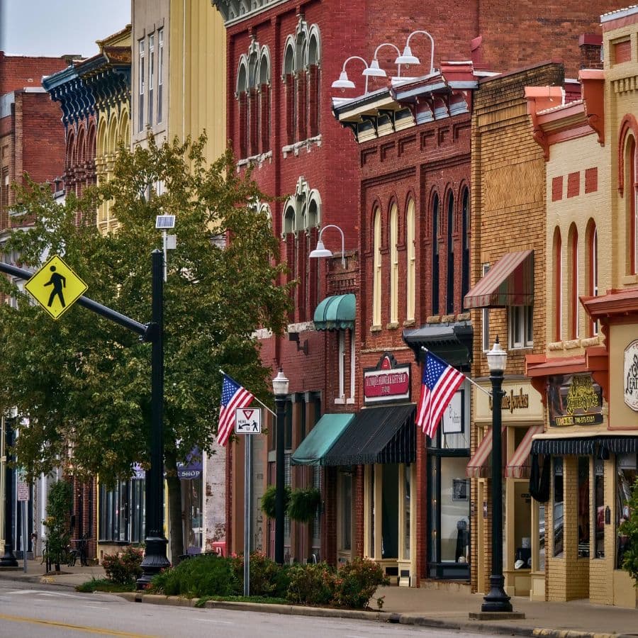 A row of historic buildings with American flags and street signs in a small town.