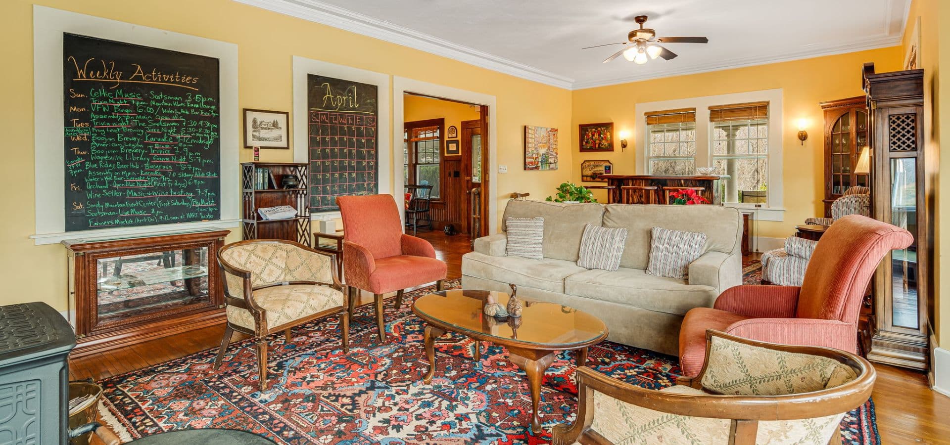 A cozy living room featuring a mix of comfortable seating, a decorative rug, chalkboard walls, and warm yellow paint.