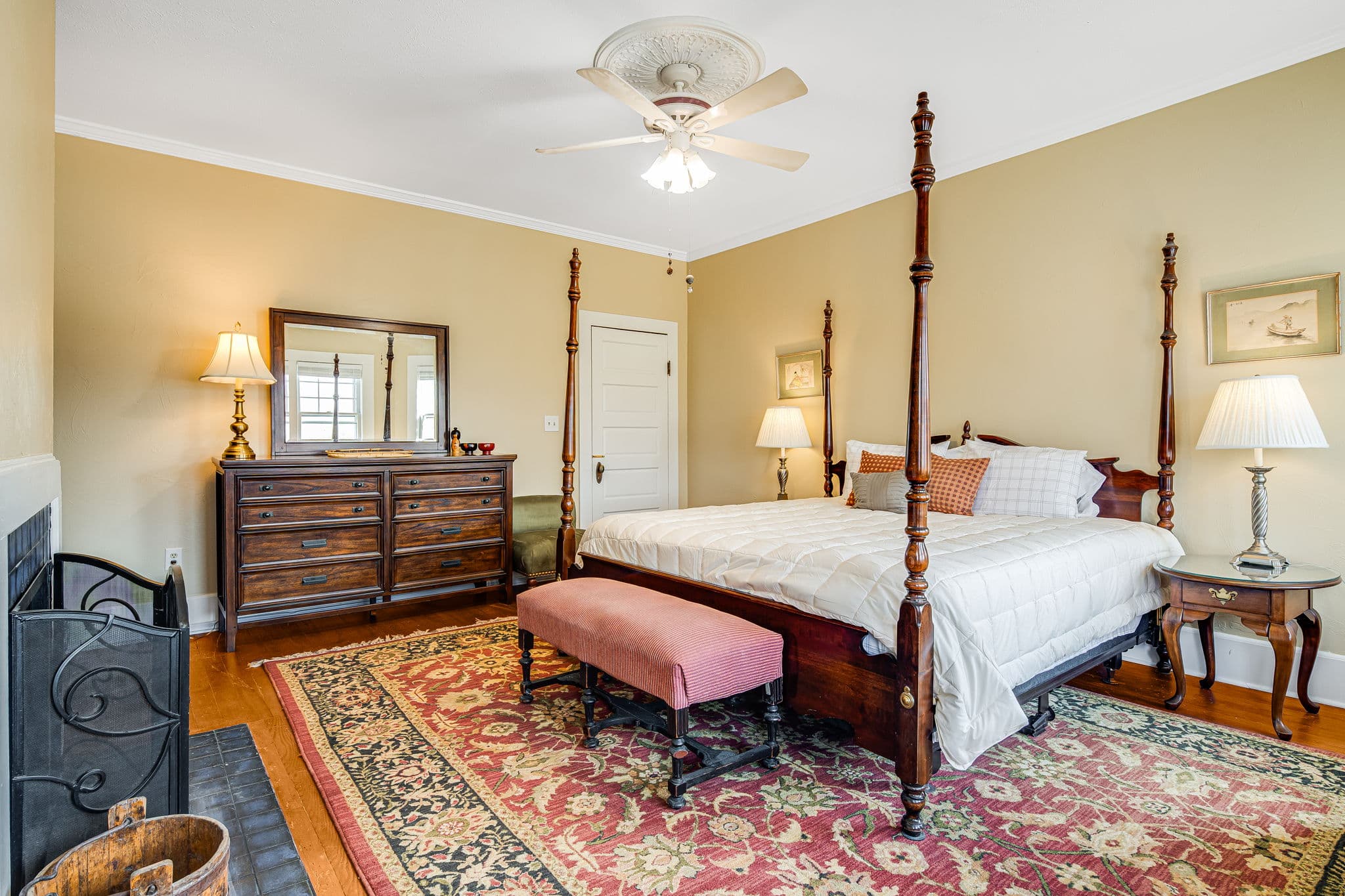 king bed, ceiling fan, oriental carpet, white bedspread, pillows, dressser