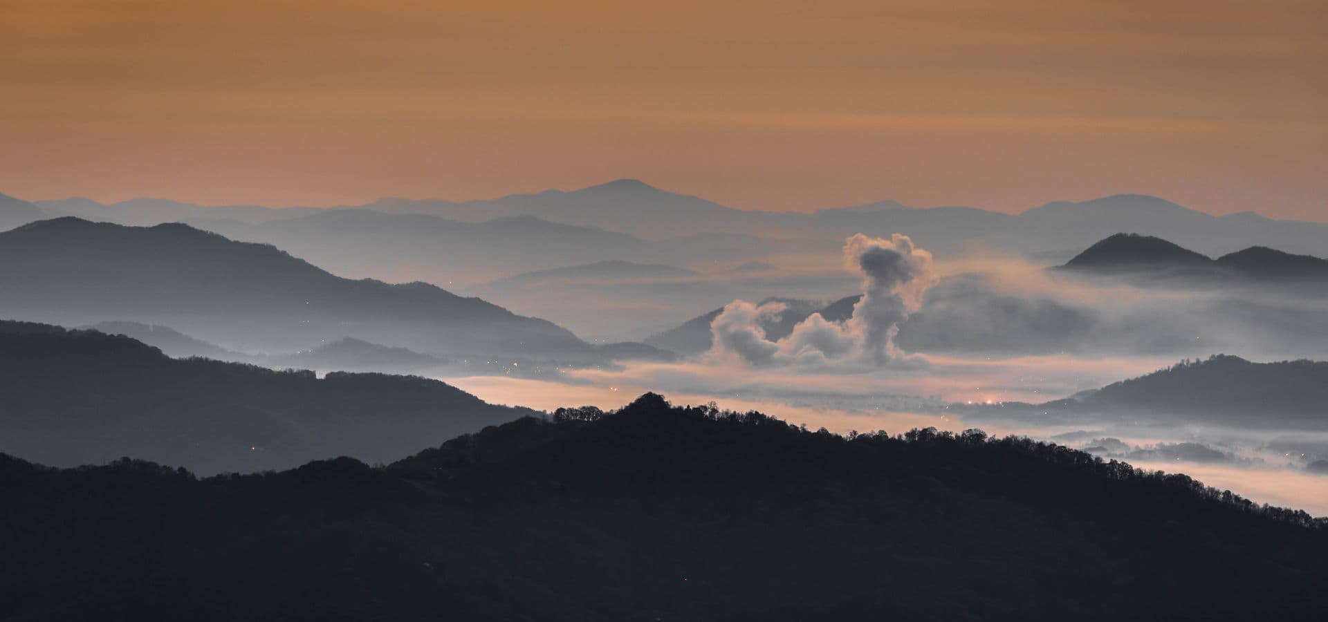 A panoramic view of misty mountains under a twilight sky.