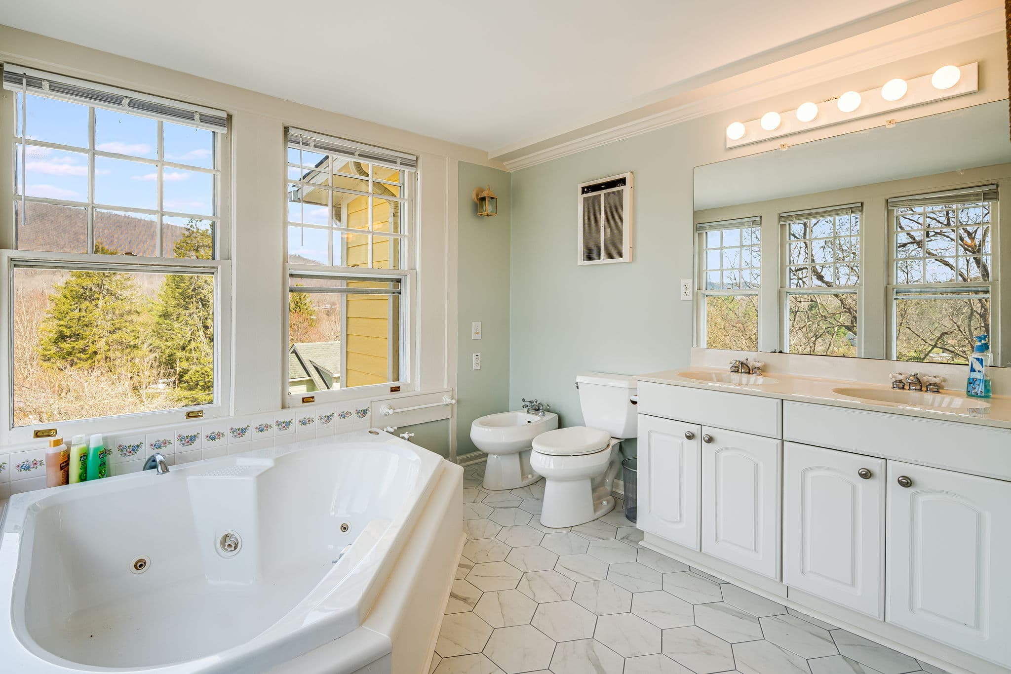 large whirlpool tub, bidet, double sink vanity, large windows, toilet, white tiled floor