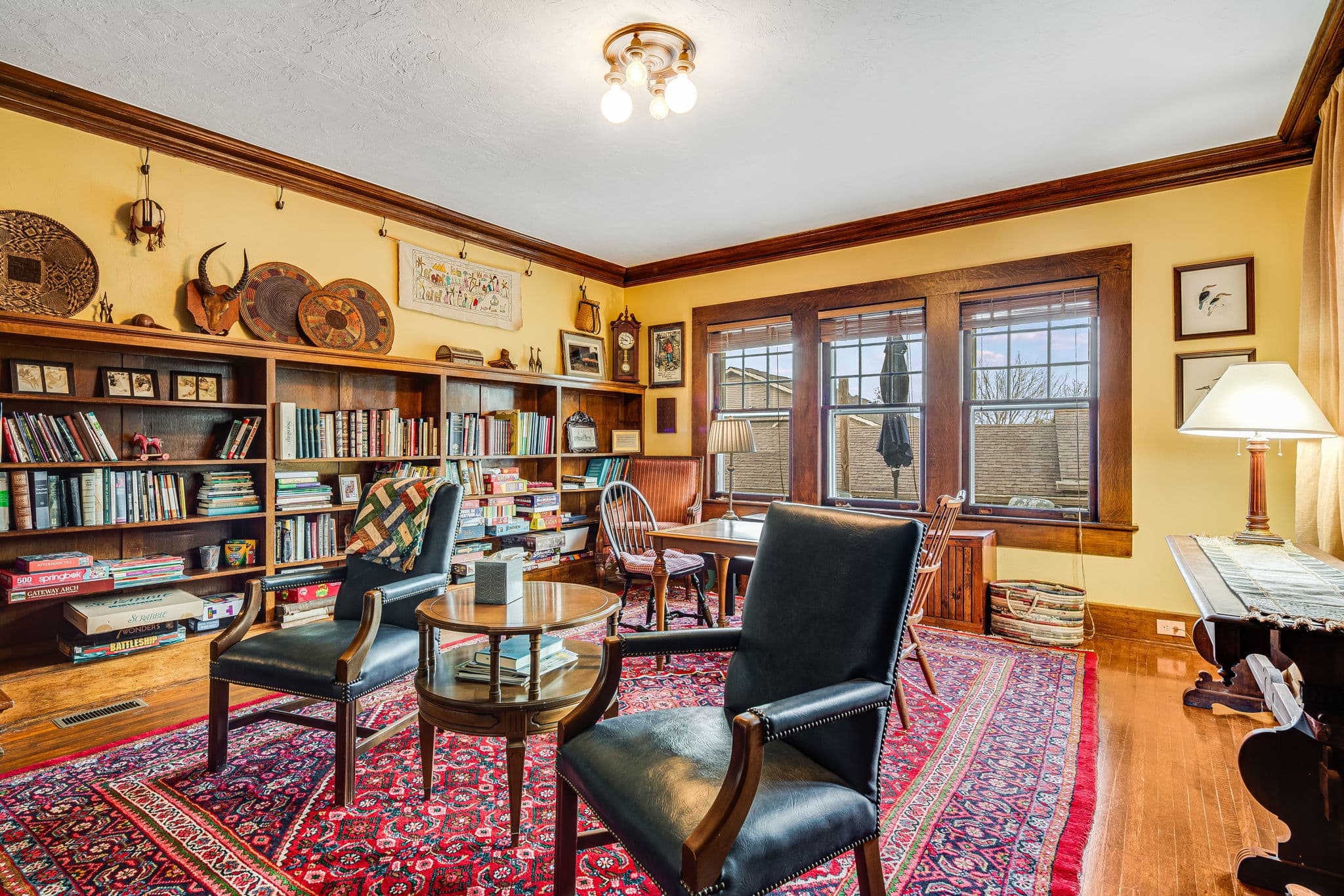 Library, international decorations, blue leather chairs, side table, windows, books, board games