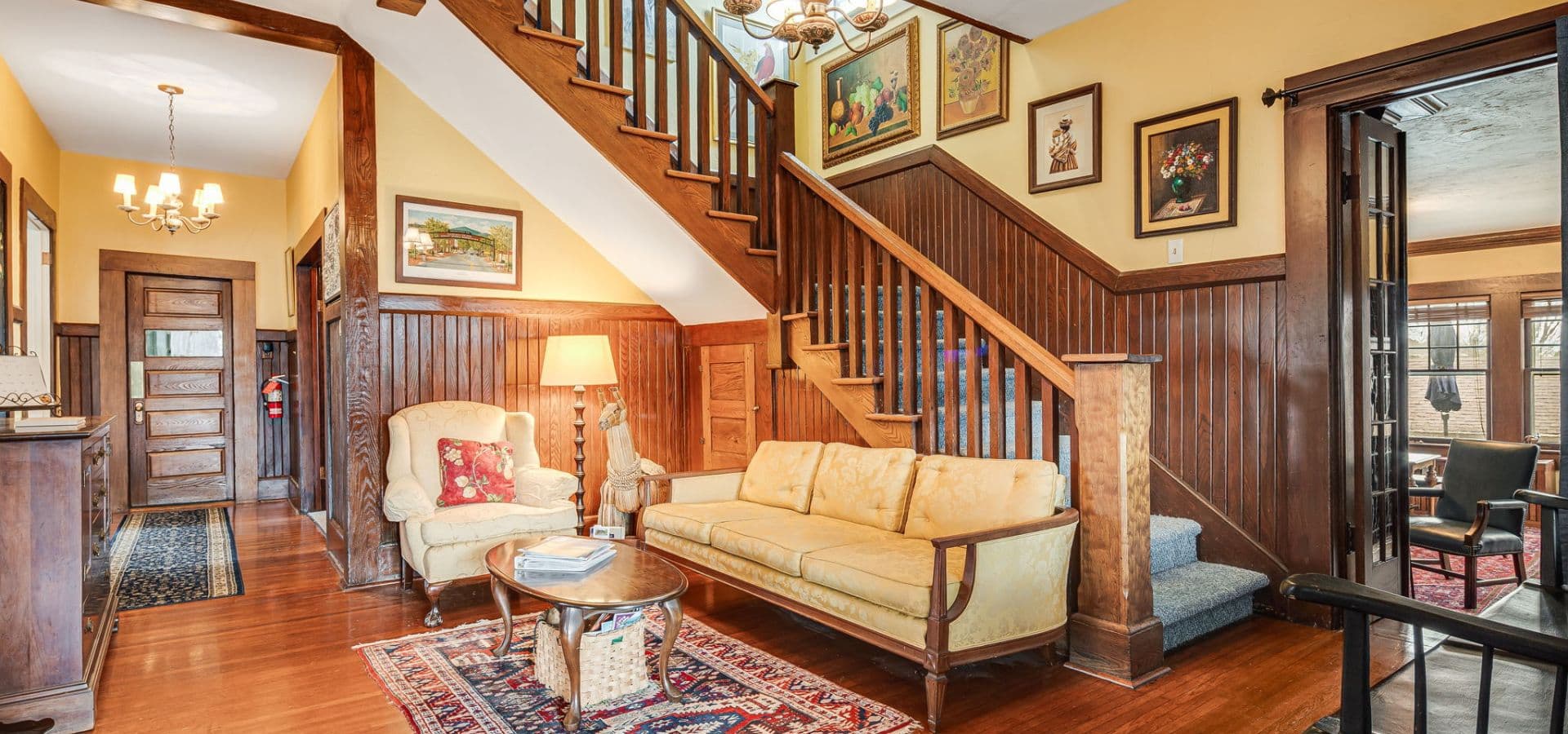 A warmly decorated entryway features a staircase, cozy seating, and artwork on the walls.