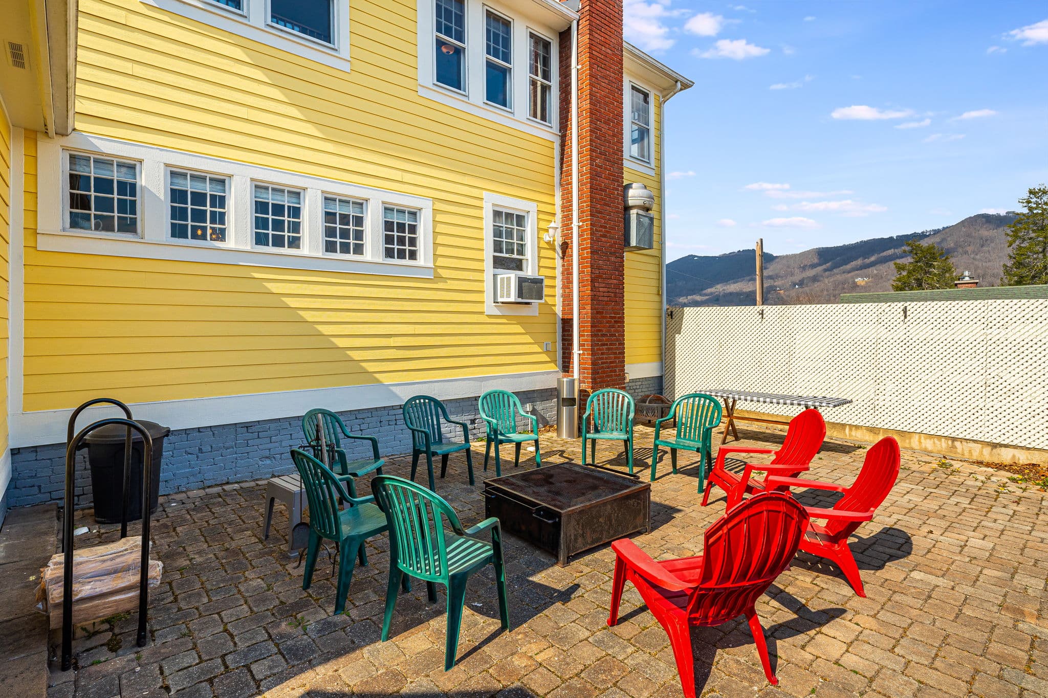 outside patio, red Adirondack chairs, fire pit, blue skies, trees, bricks