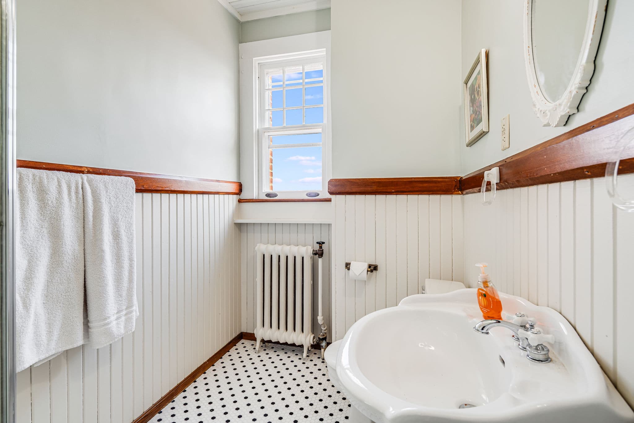 bathroom with sink, mirror, window, black and white tiled floor