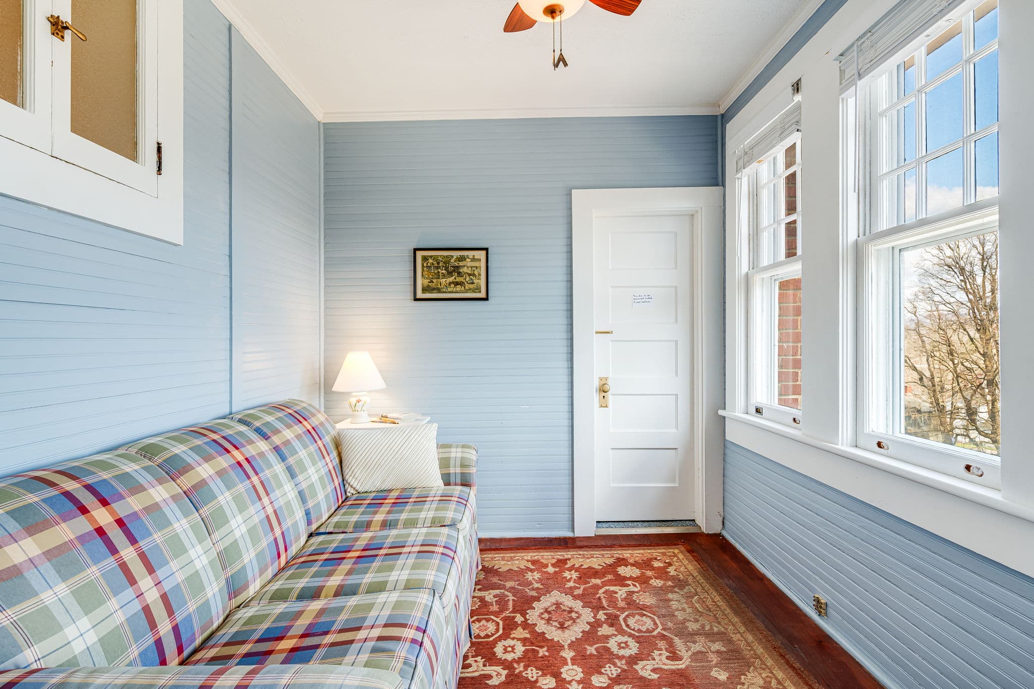 pullout sofa bed, oriental carpet, light blue walls, ceiling fan, windows